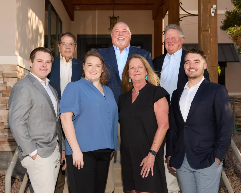 A group photo of the Woodruff Wealth team, posed together outside of their office building, reflecting their unity, professionalism, and the architectural backdrop of their workplace.
